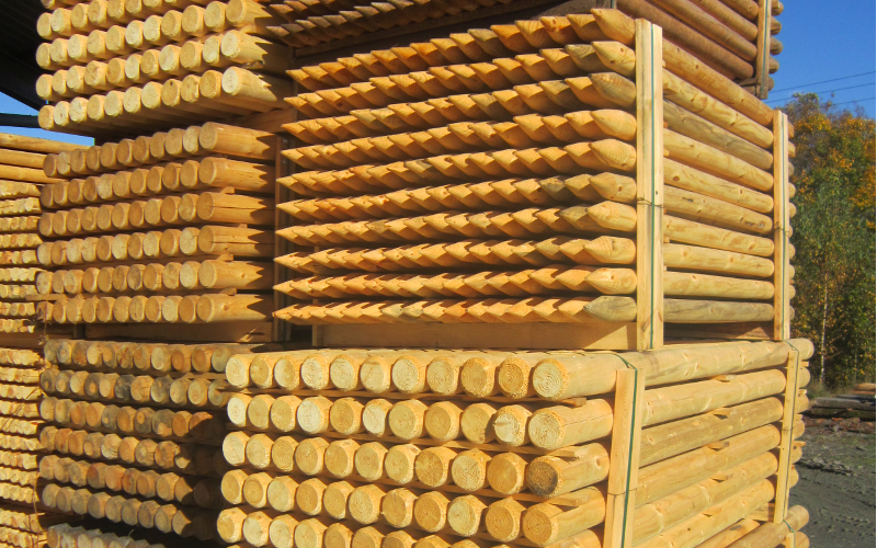 Lager mit Holzstapeln aus Rundhölzern für den Zaunbau