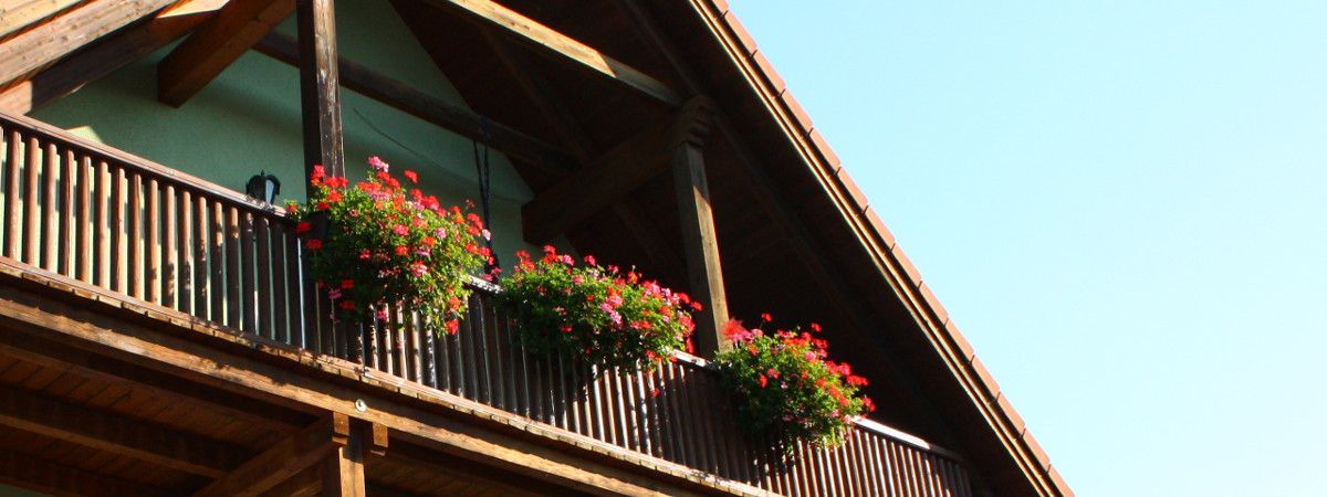 Geranien in Pflanzenkübeln am Balkon eines Hauses