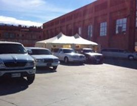 Coches aparcados delante de una tienda de campaña de color canela cerca de un edificio de ladrillos en un día soleado.