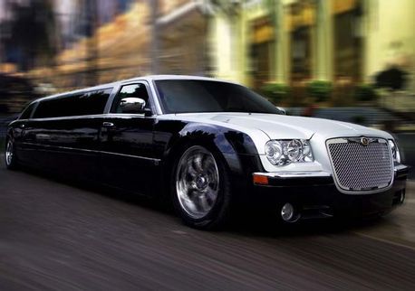 Limusina Chrysler 300 negra y plateada en una calle de la ciudad, efecto de desenfoque de movimiento.