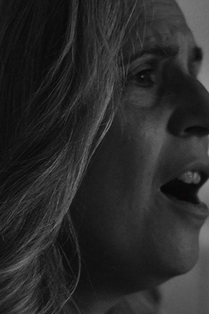 Rostro de mujer en blanco y negro, boca abierta en expresión de sorpresa o angustia, mirando hacia un lado.