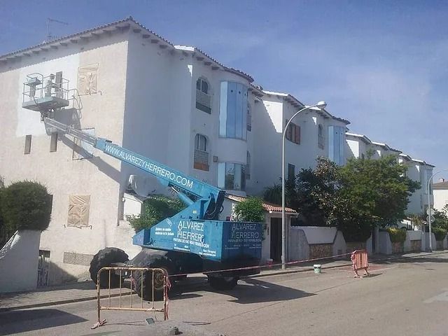 Se está utilizando una grúa azul para pintar un edificio.