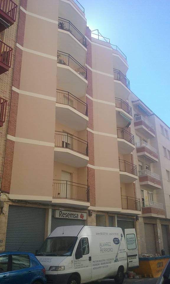 Una camioneta blanca está estacionada frente a un edificio alto.
