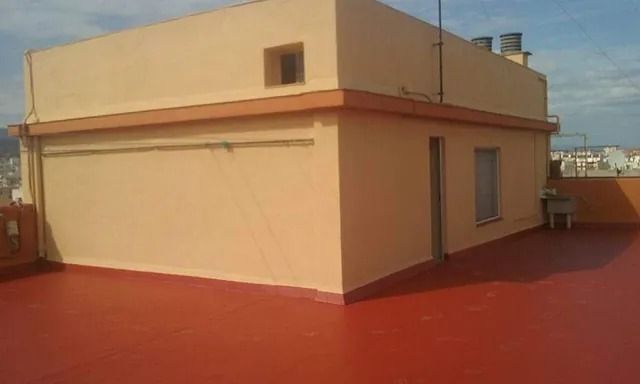 Un edificio con un techo rojo y una ventana en un costado.