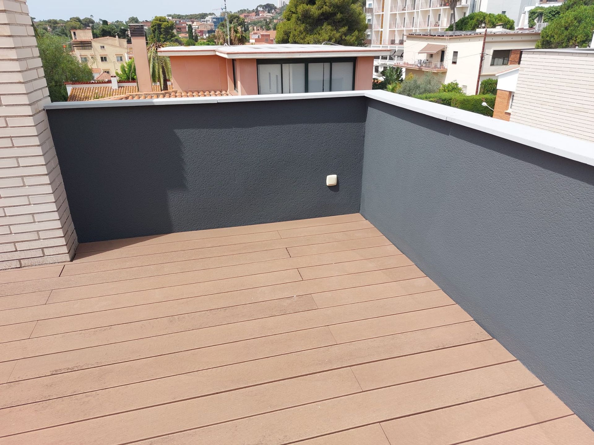Un balcón con suelo de madera y pared de ladrillo.