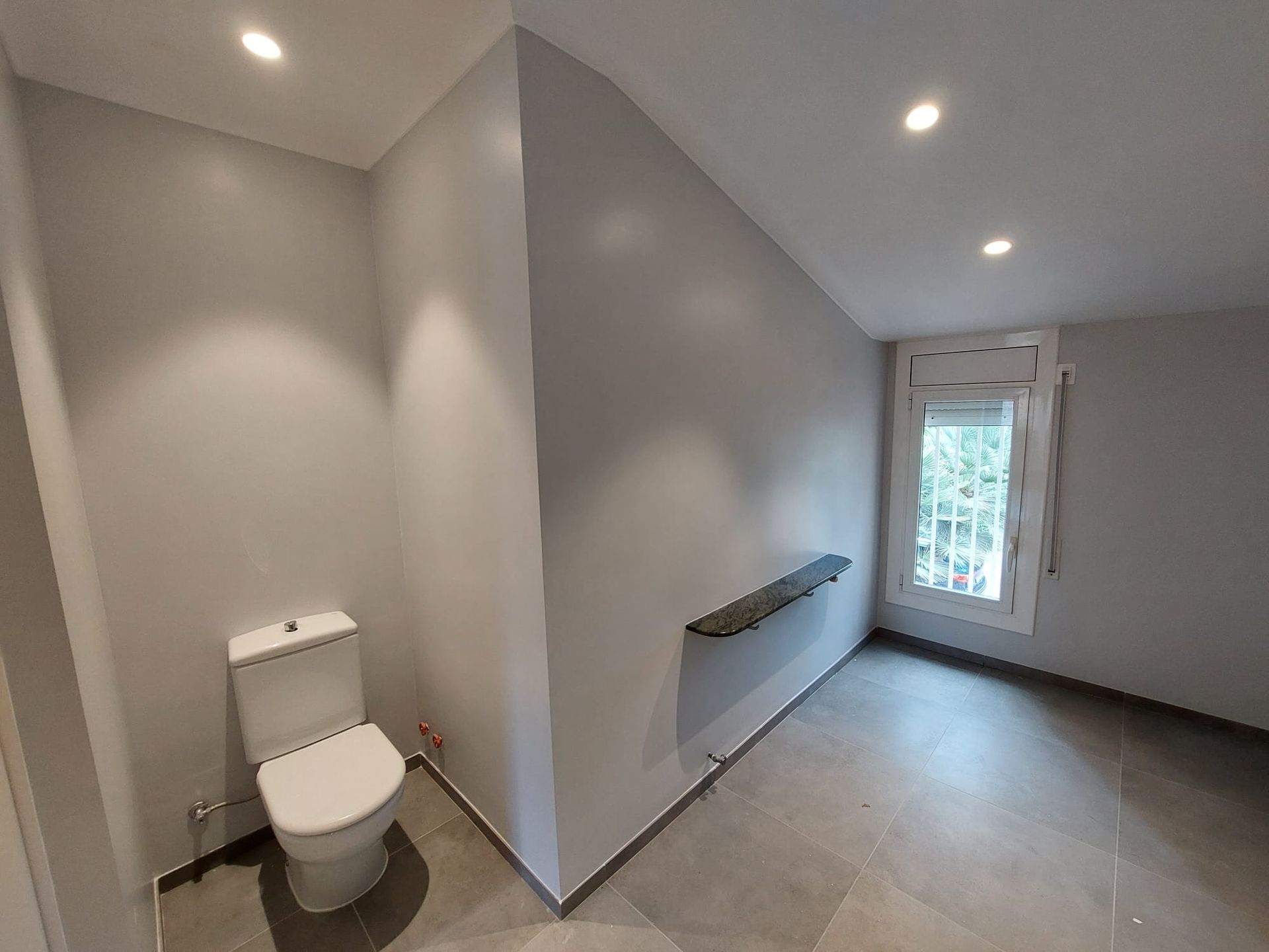 Un baño vacío con un inodoro y una ventana.
