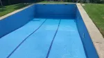 Una piscina vacía con azulejos azules y una escalera.