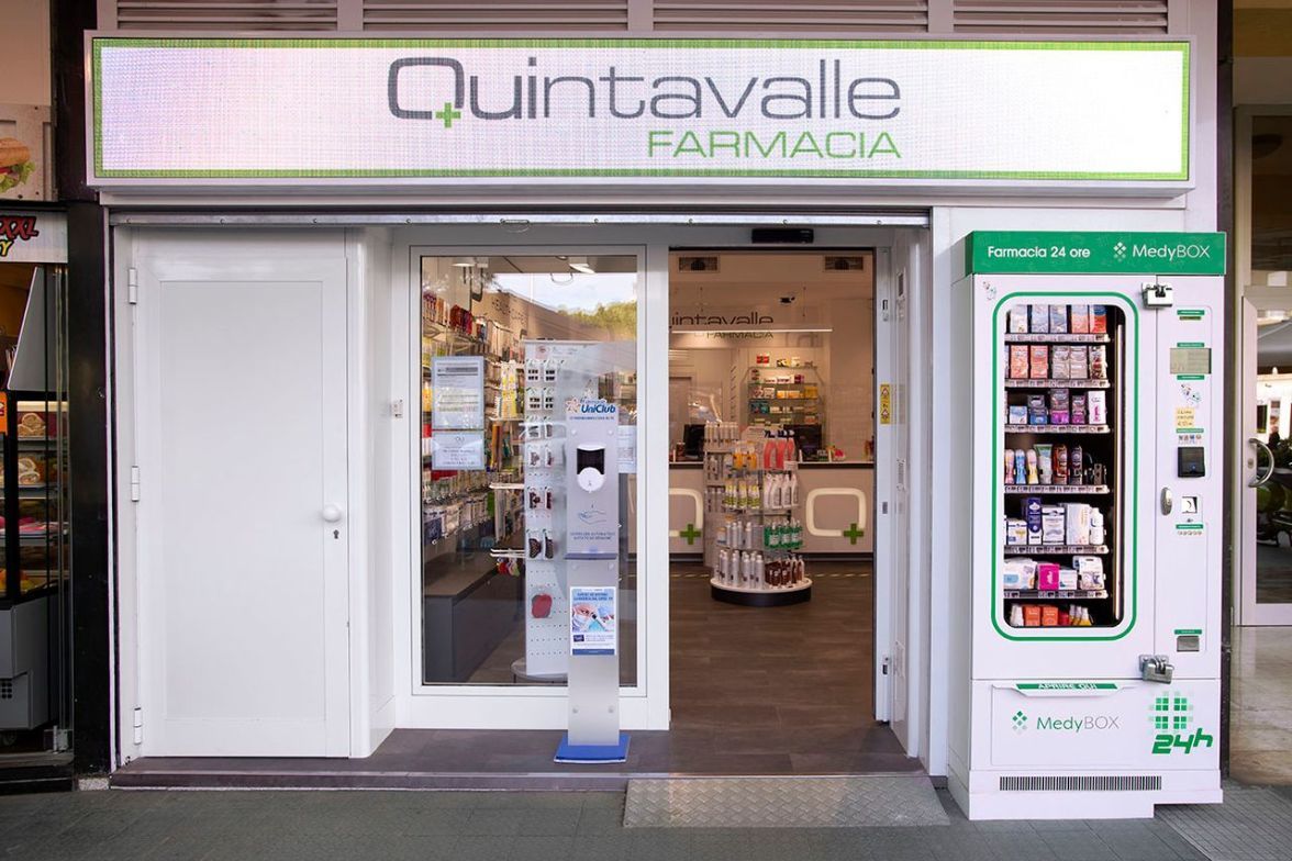 Esterno della facciata della Farmacia Quintavalle con ingresso aperto e distributore automatico sulla destra.
