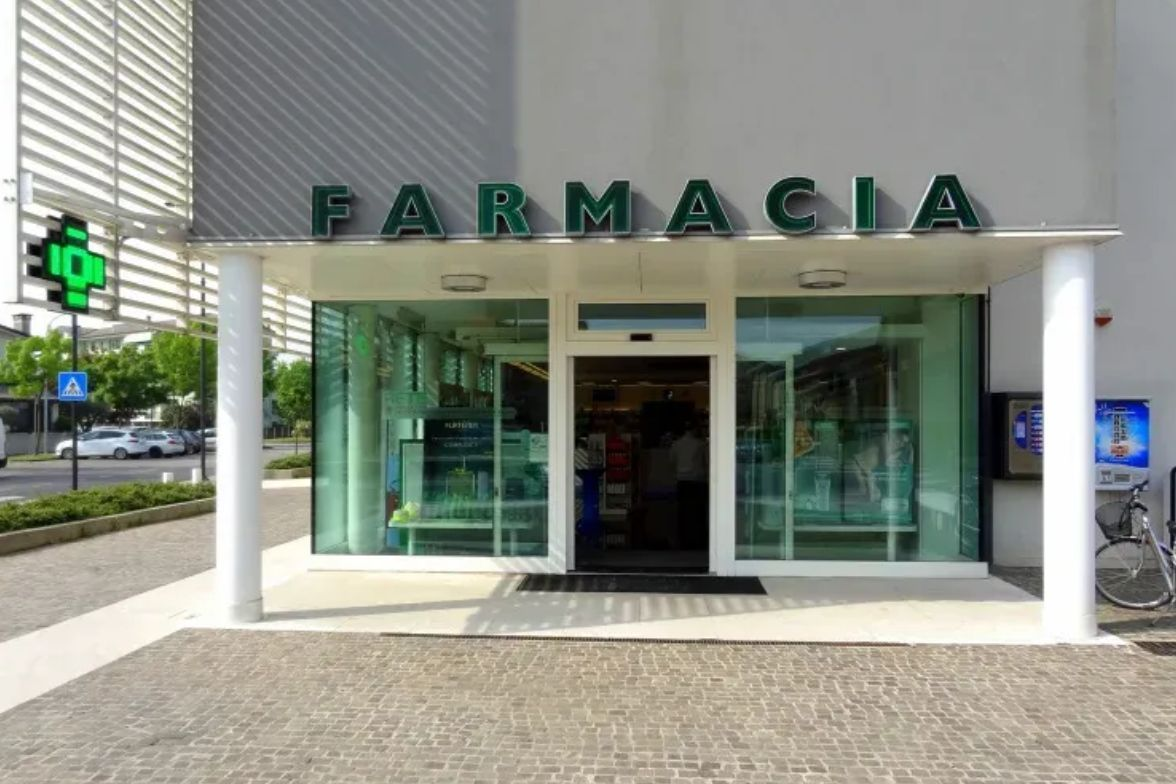 Vetrina della farmacia con porte a vetri e insegna verde