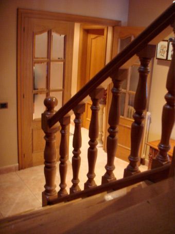 Una escalera con barandilla de madera y puerta de cristal.