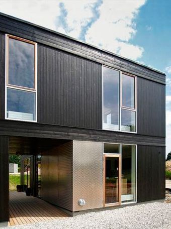 Una casa negra con muchas ventanas y una puerta de acero inoxidable.