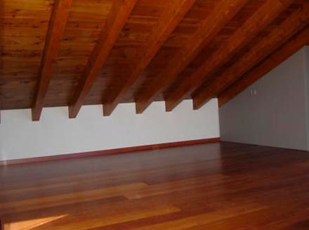 Una habitación vacía con suelo de madera y techo de madera.