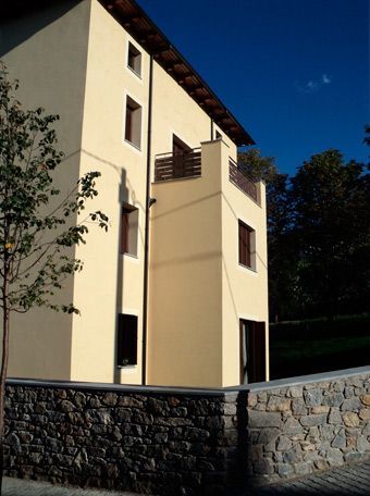 Un edificio amarillo con un muro de piedra delante.
