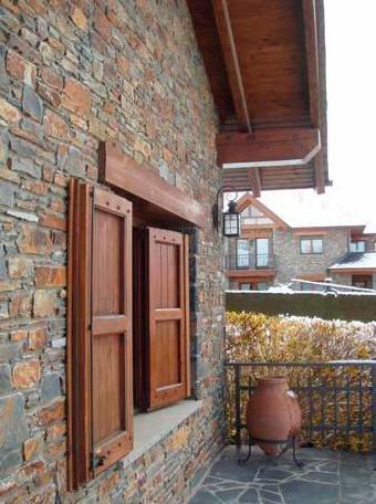 Un edificio de ladrillo con contraventanas de madera en las ventanas