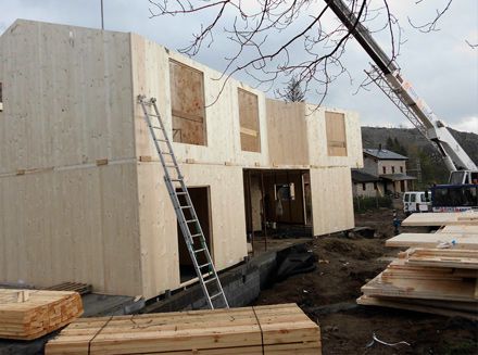 Se está construyendo una casa de madera con una grúa al fondo.