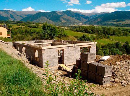 Se está construyendo una casa en una colina con montañas al fondo.