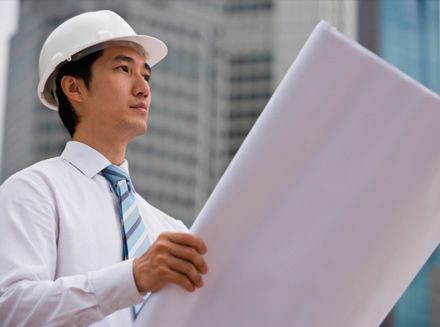 Un hombre que lleva casco y corbata está mirando un plano.
