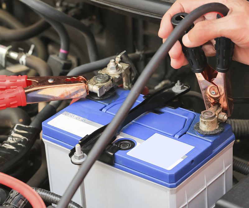 Una persona está cargando la batería de un automóvil con cables puente.