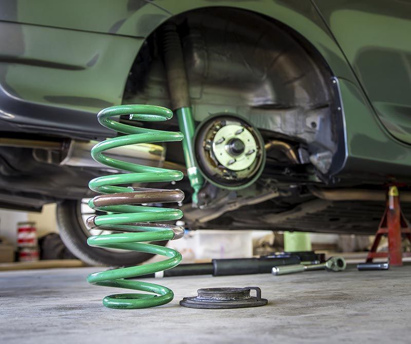 Un manantial verde está debajo de un coche en un garaje.