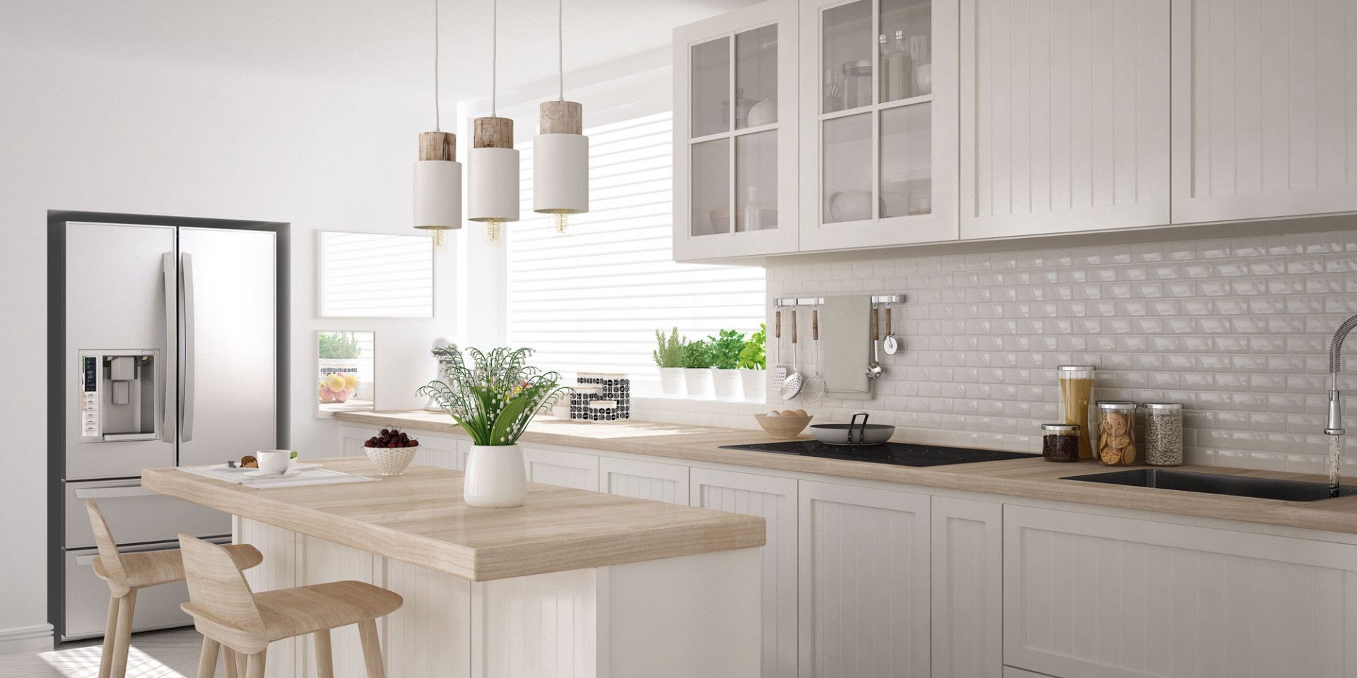 Moderne weiße Küche mit Kochinsel aus Holz, Edelstahlkühlschrank und Hängelampen.