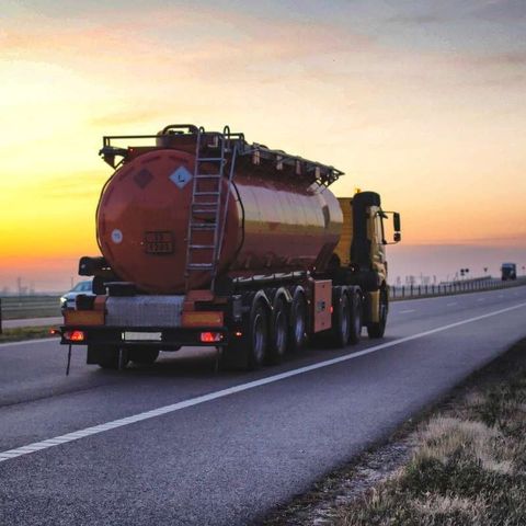 Un camión cisterna circula por una autopista al atardecer.