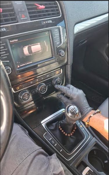 Une personne règle les commandes de la climatisation de sa voiture à l'aide de manomètres reliés au tableau de bord.