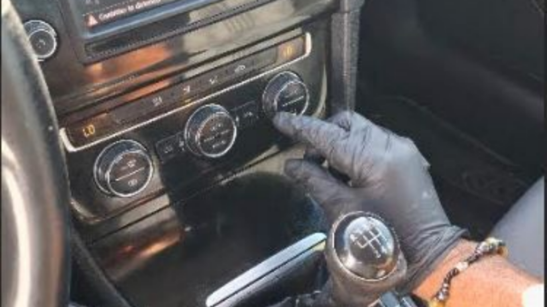 Une personne teste la climatisation d'une voiture à l'aide de manomètres.