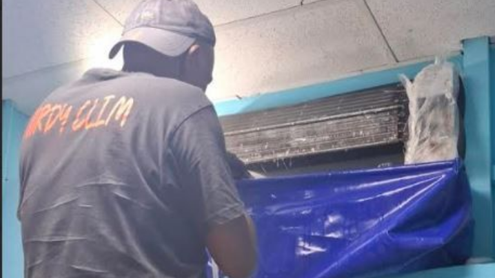 Un homme nettoie un climatiseur.