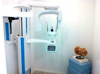 Una máquina de rayos X está en una habitación al lado de un jarrón de flores.