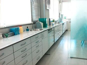 Una cocina con fregadero, armarios, cajones y una puerta corrediza de cristal.