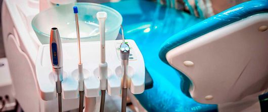 Un primer plano de una silla dental con instrumentos dentales sobre ella.