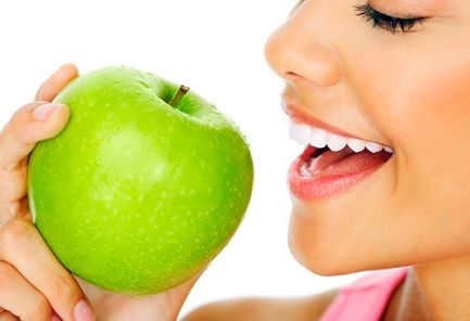 Una mujer está comiendo una manzana verde con la boca abierta.