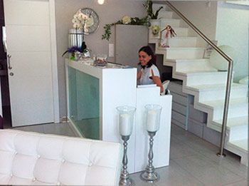 Una mujer está de pie en un mostrador de recepción en una habitación con escaleras.