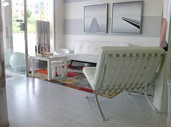 Una sala de estar con un sofá, una silla, una mesa y cuadros en la pared.