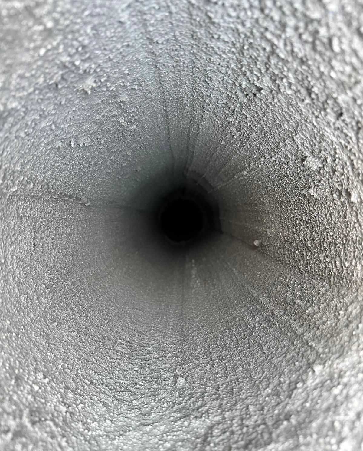 Nahaufnahme in ein frostiges, strukturiertes Rohr oder einen Tunnel mit einem dunklen, kreisförmigen Zentrum