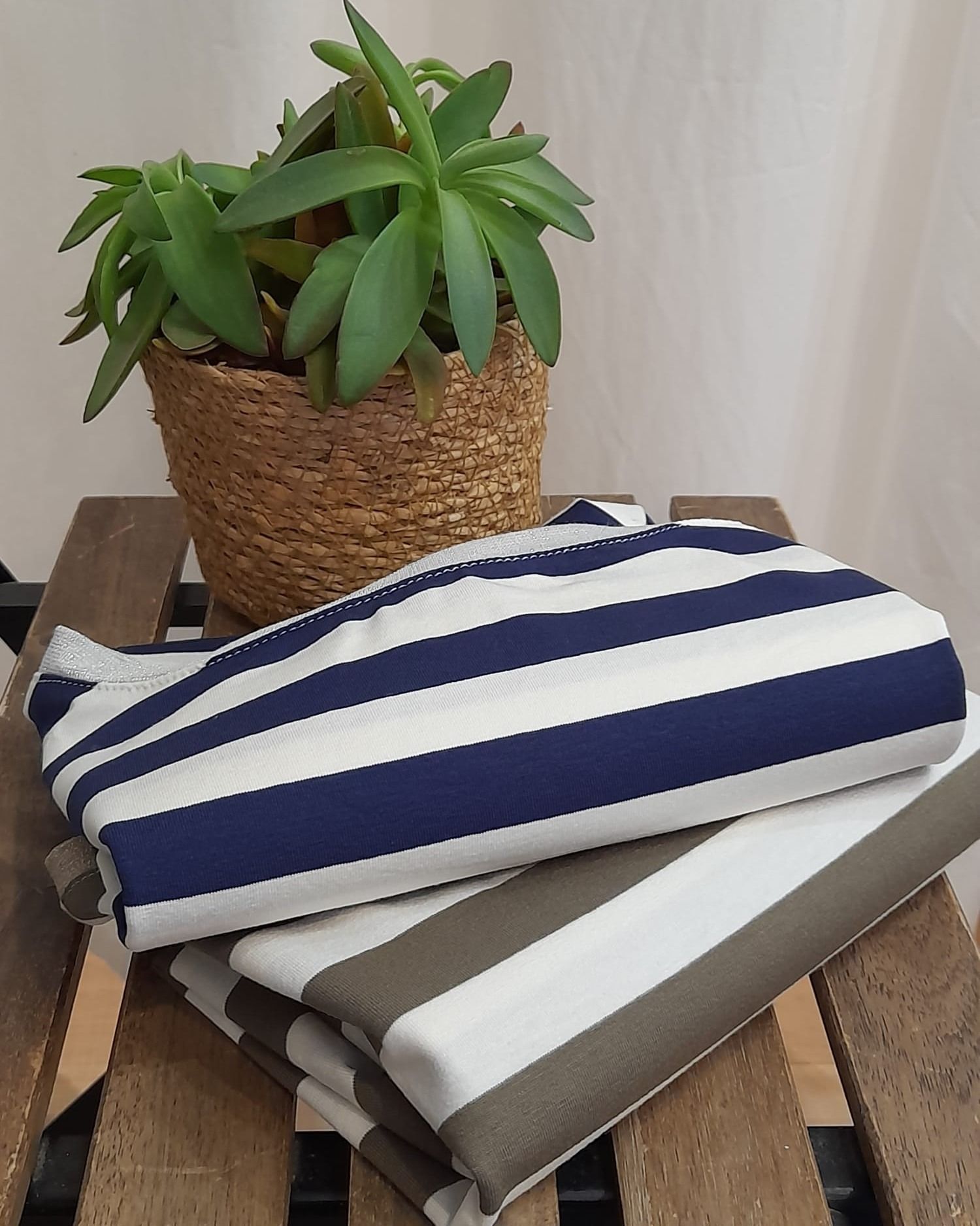 Una toalla rayada está sobre una mesa de madera al lado de una planta en maceta.