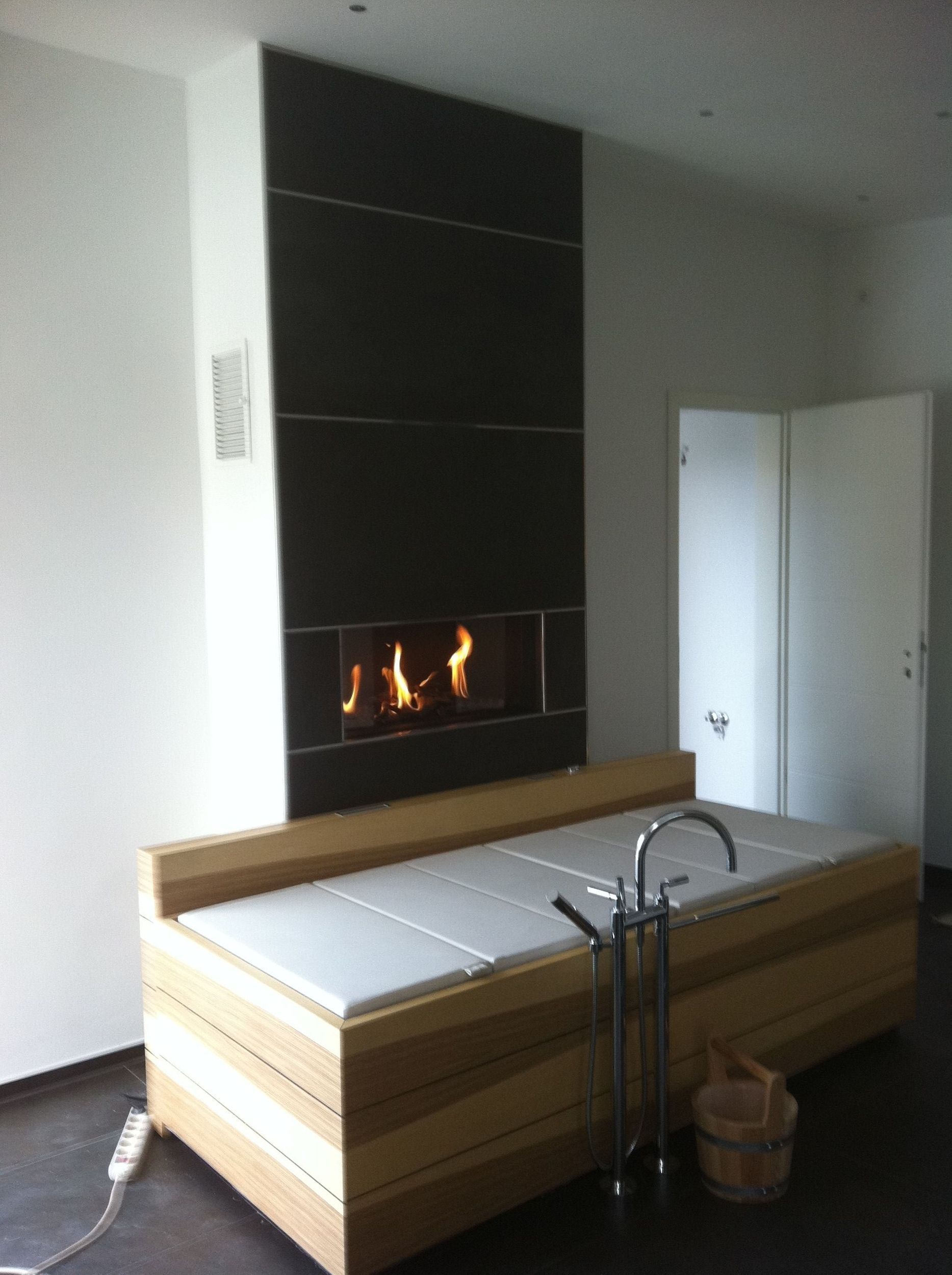 Eine Badewanne in einem Badezimmer mit einem Kamin dahinter