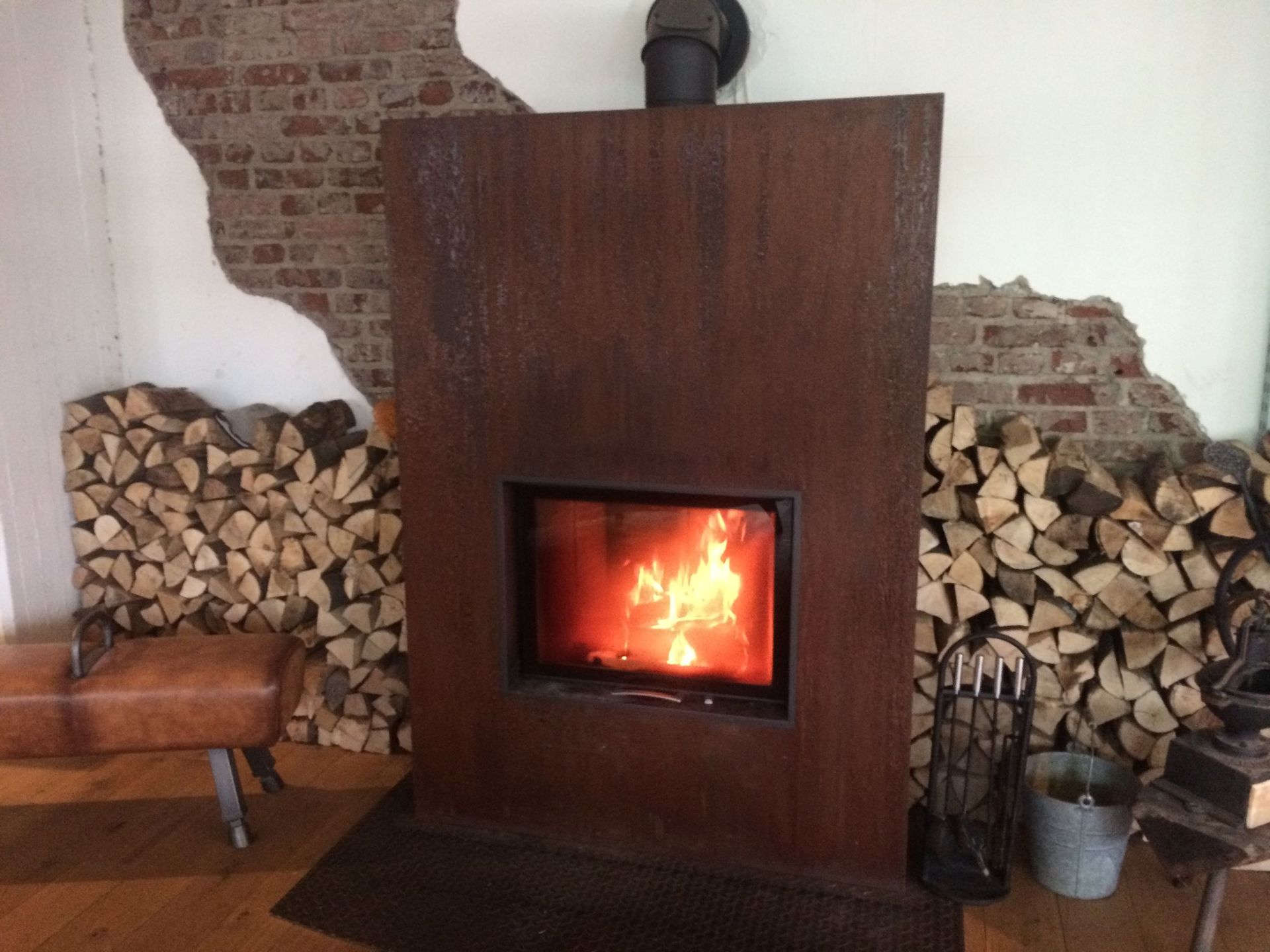 Vor einem Stapel Holzscheite steht ein Kamin.