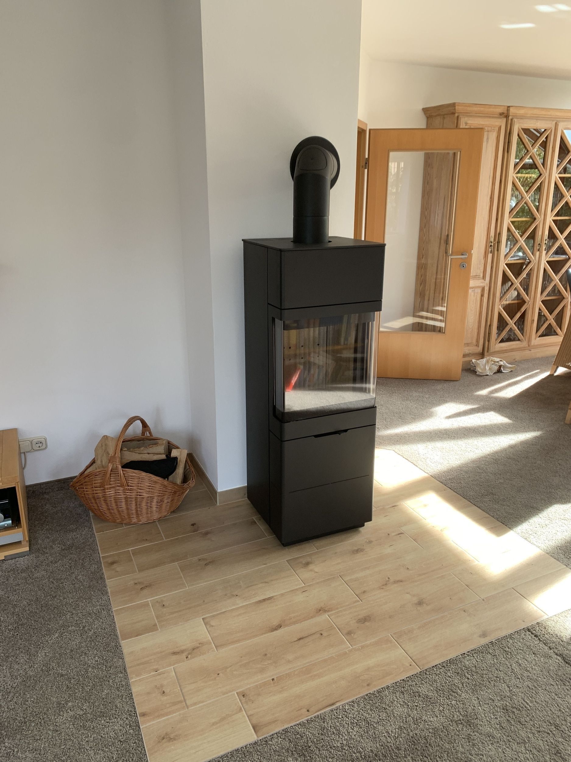 In der Mitte eines Wohnzimmers steht ein schwarzer Kamin.