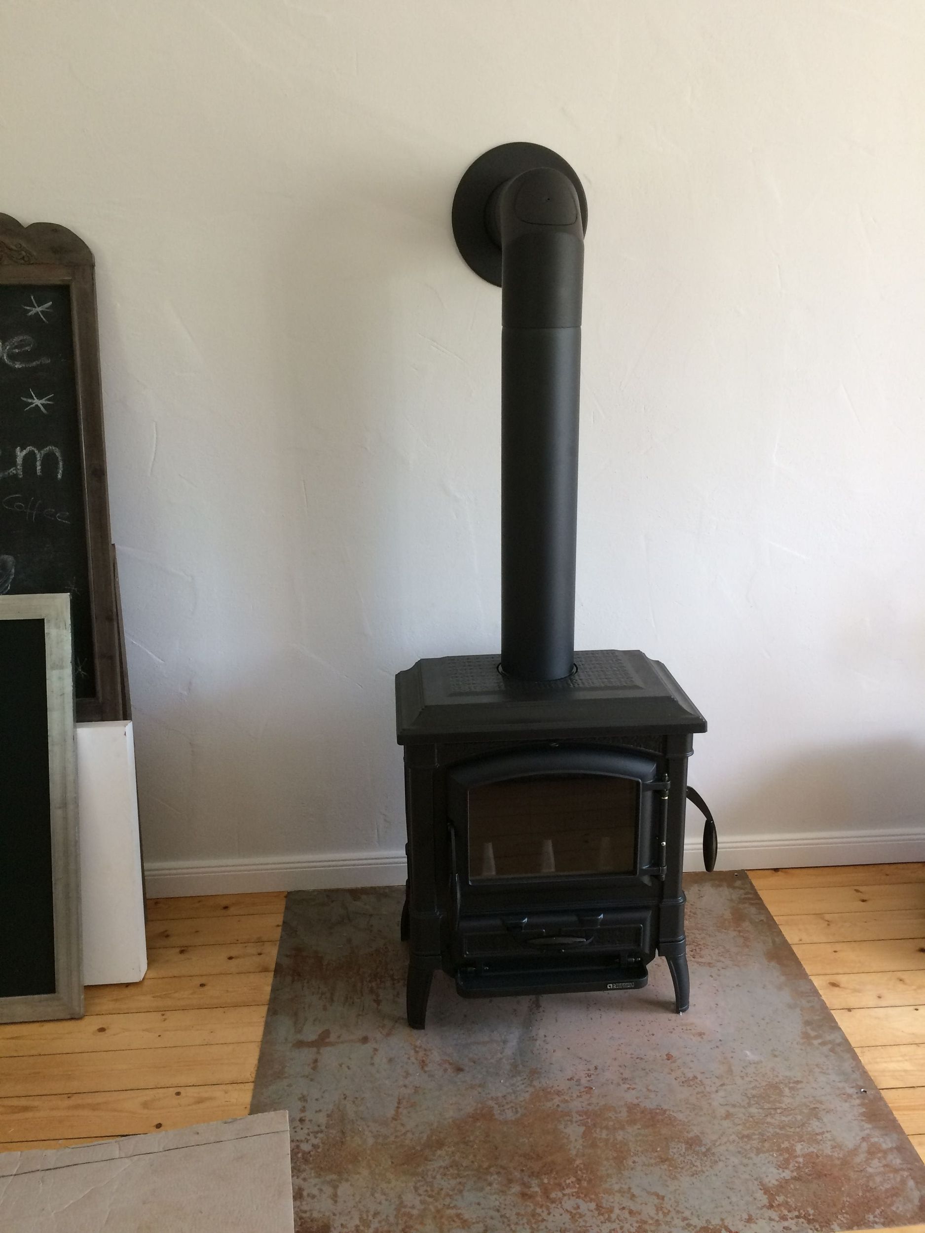 Ein schwarzer Holzofen steht auf einem Teppich in einem Wohnzimmer.