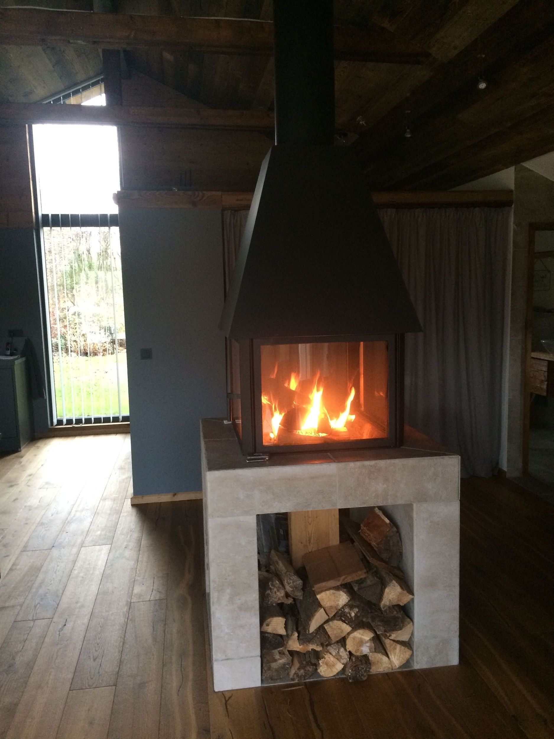 In der mitte des raumes steht ein kamin mit viel holz darin.