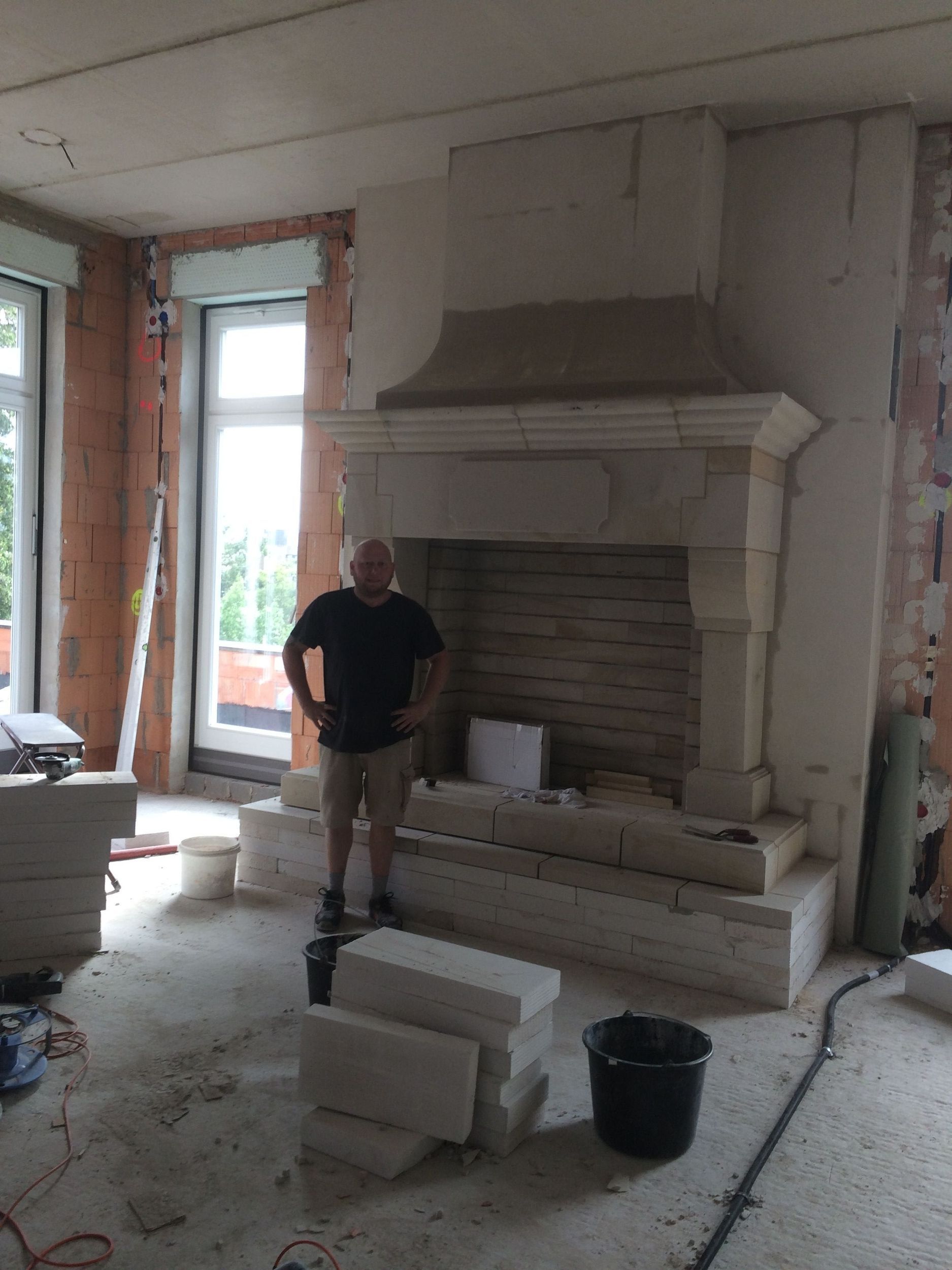 Ein Mann in einem schwarzen Hemd steht vor einem Kamin