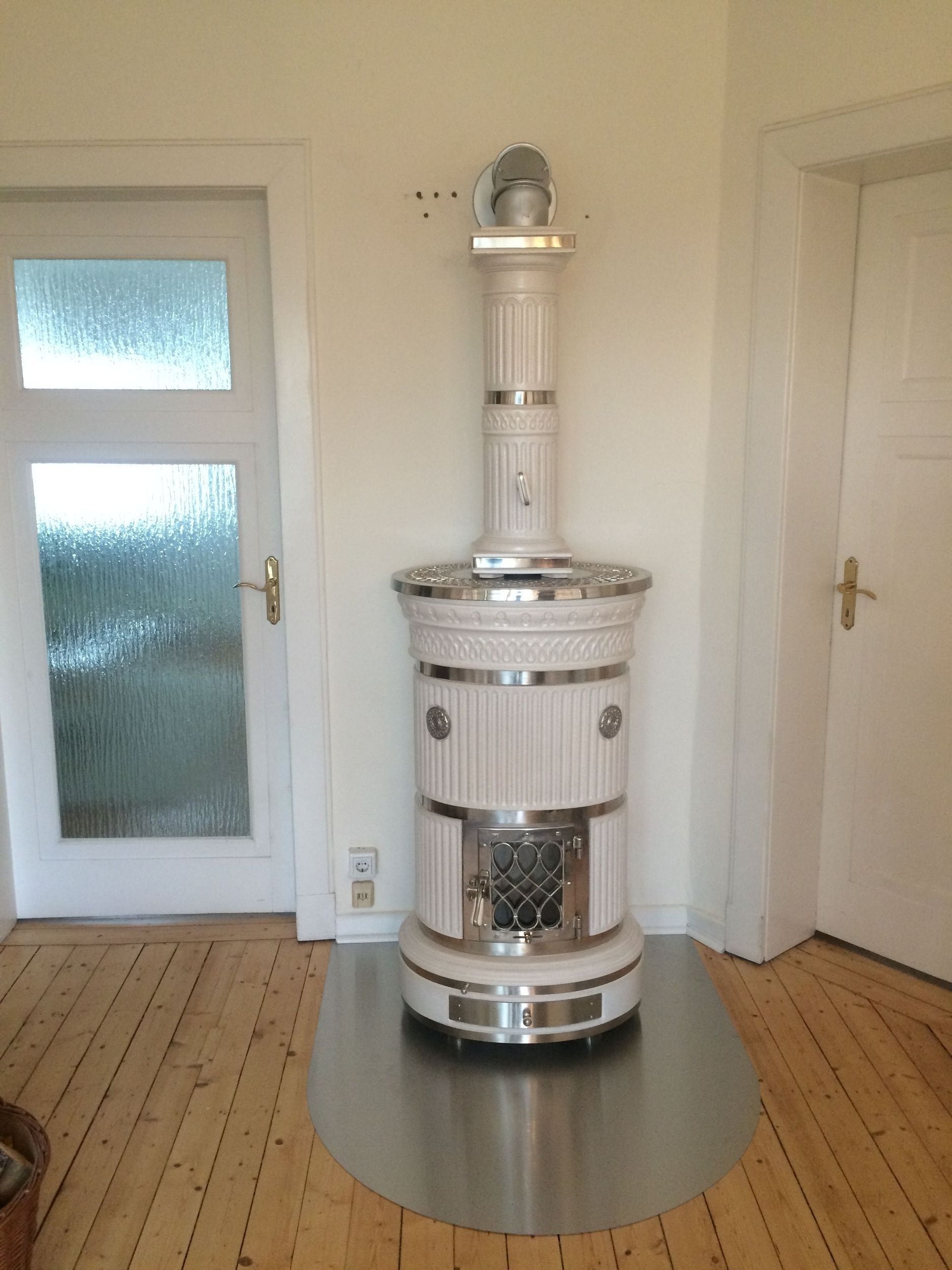 In einem Raum steht ein weißer Ofen auf einem Holzboden.