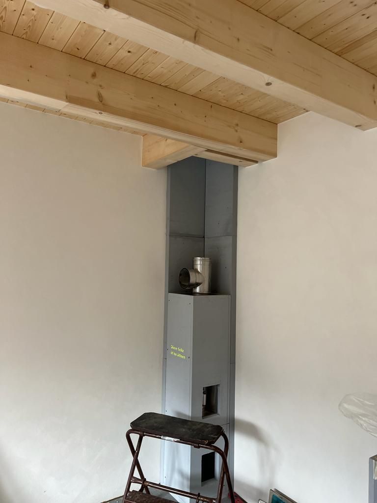 Ein Raum mit Holzdecke und einem Kamin in der Ecke