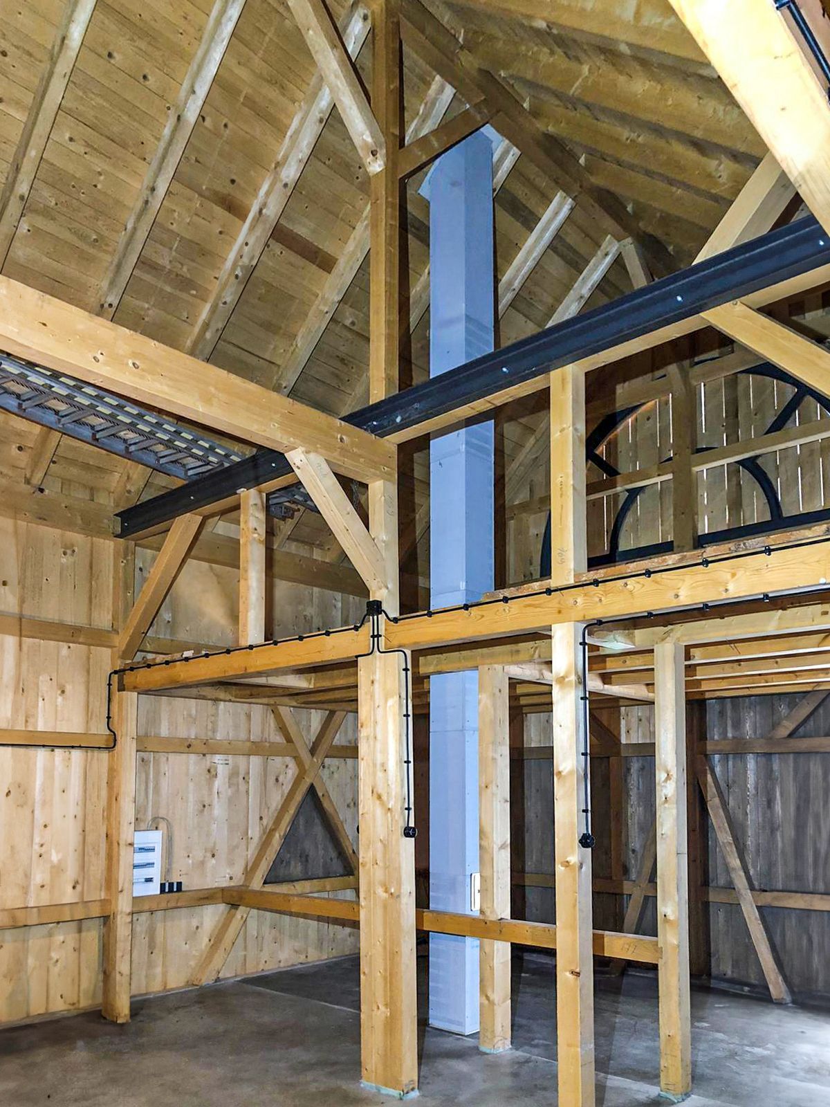 Das Innere eines Holzgebäudes mit einem Schornstein in der Mitte.