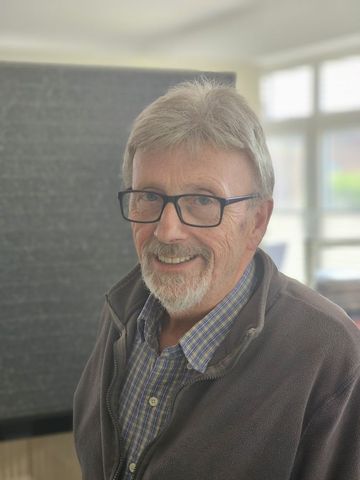 Ein Mann mit Brille und Bart lächelt in die Kamera.