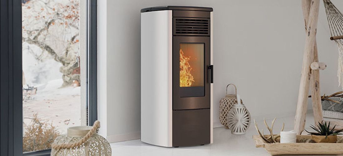 Ein weißer Pelletofen steht in einem Wohnzimmer neben einem Fenster.