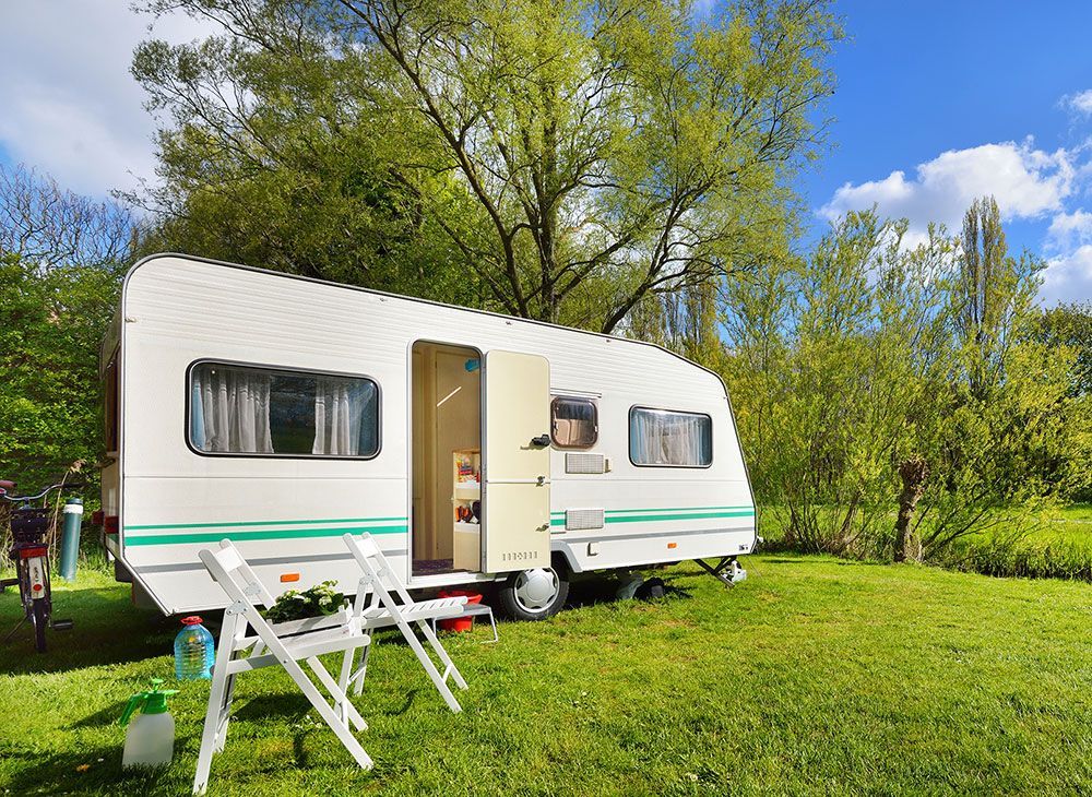 caravane posé dans l'herbe avec des chaises devant