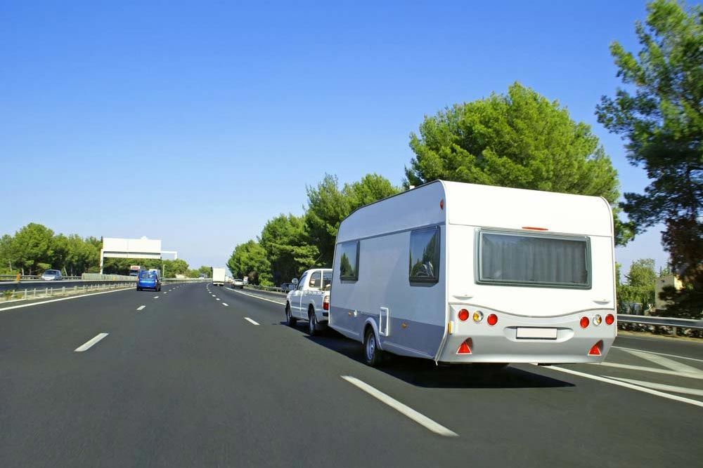 caravane tracté par une voiture sur une voie rapide