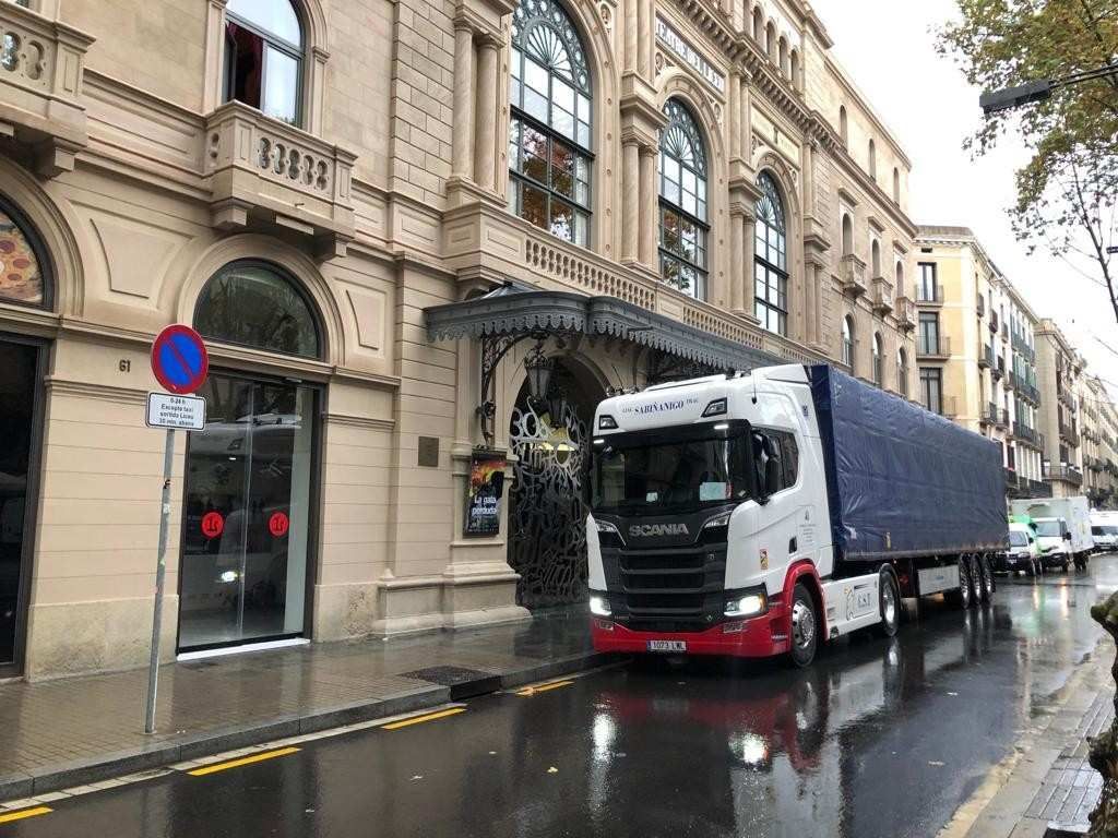 Camión que transporta troncos en una carretera que serpentea a través de un colorido bosque otoñal.